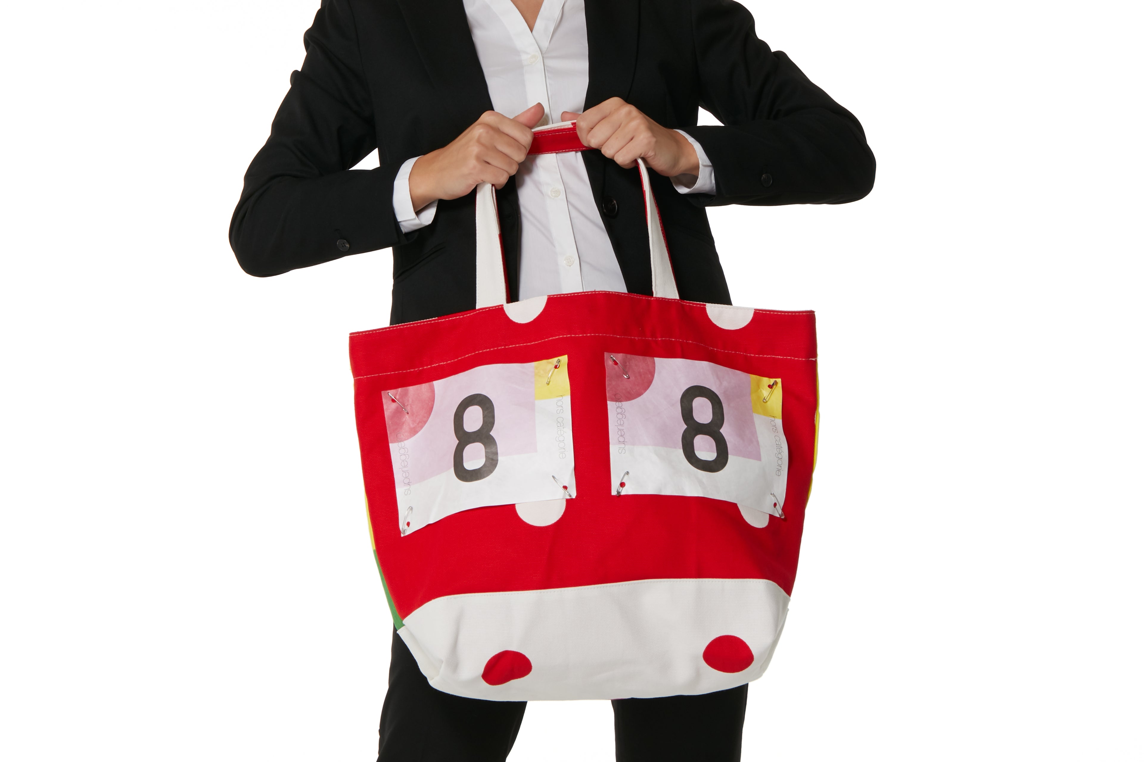 Person holding a red tote bag with numbers and polka dots on a white background featuring Superleggero branding