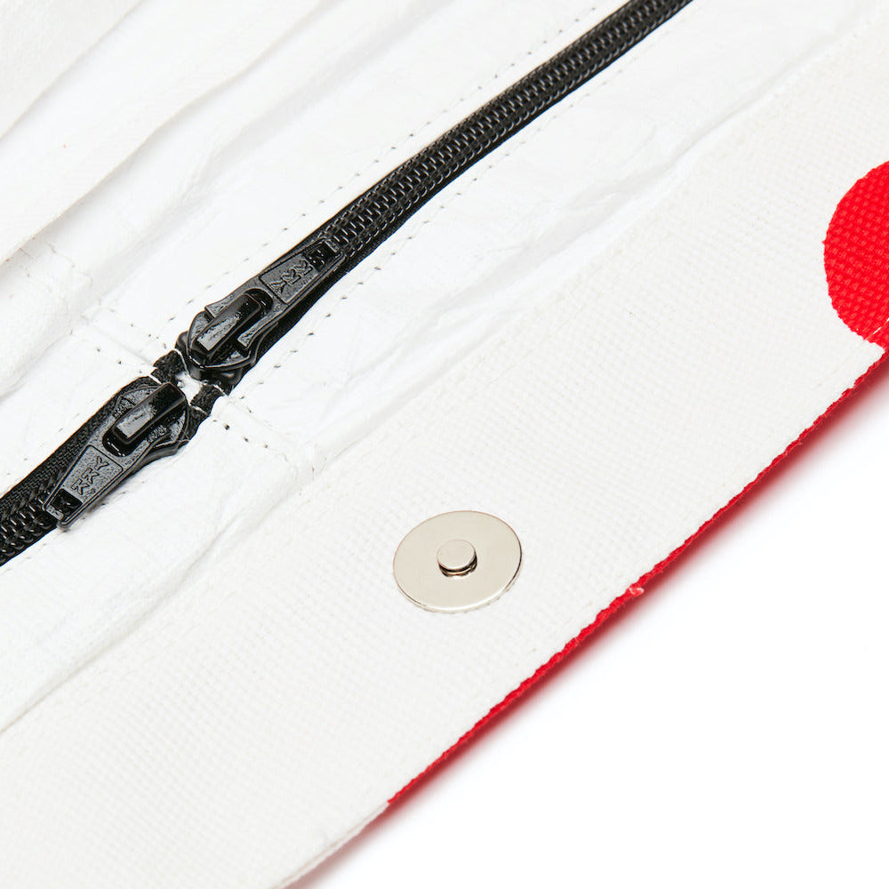 Close-up of a black zipper on a white background with a red thread.
