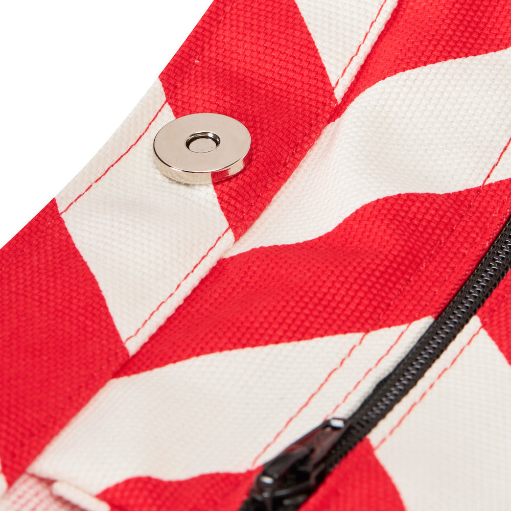 Close-up of a red and white striped fabric with a zipper and button.