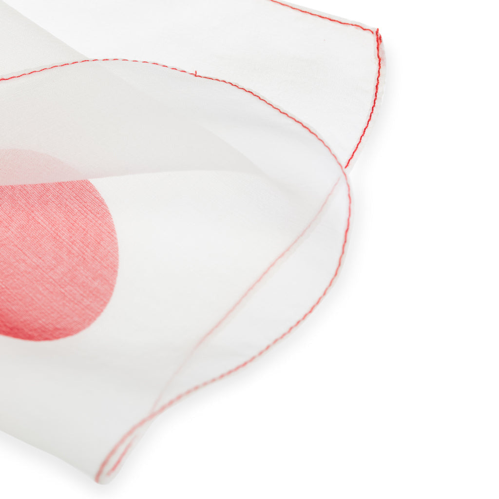 Close-up of a white silk foulard with polkadot design and red stitching on a white background
