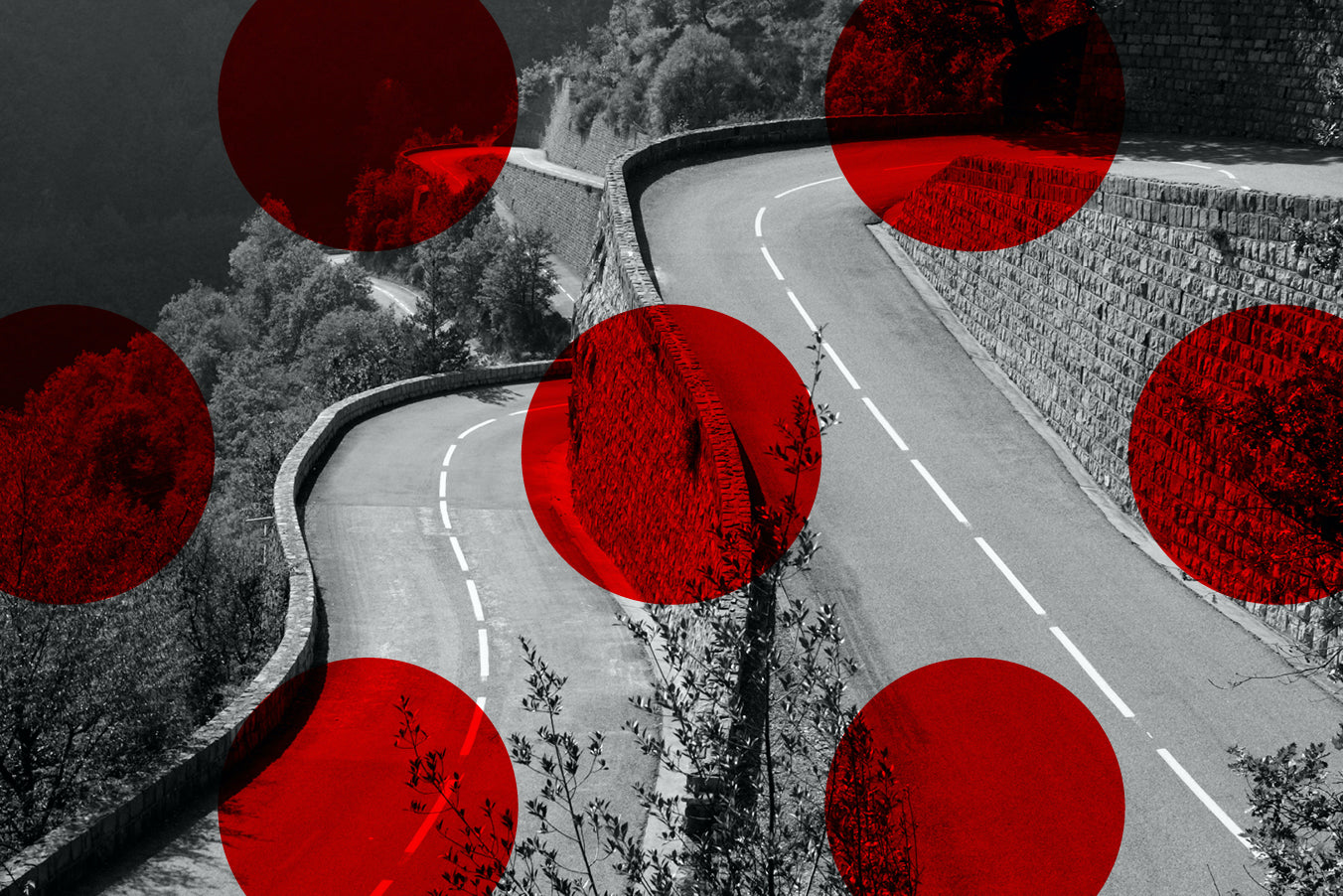 A black and white photograph of a winding mountain road bordered by stone walls and trees, overlaid with several large translucent red dots.